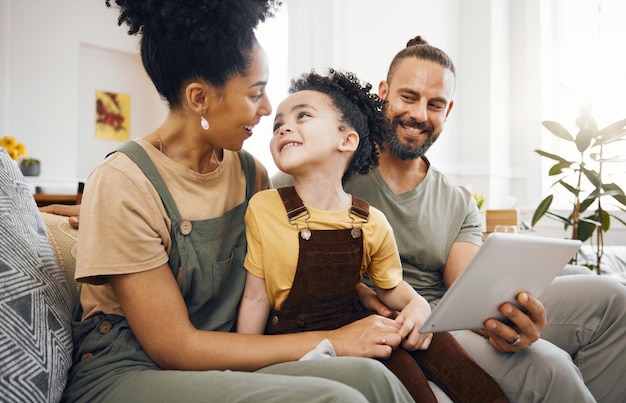 Photo home family and parents with a tablet boy and connection with games cartoon and relax people mother or father with their son child or kid on a sofa technology or social media with conversation