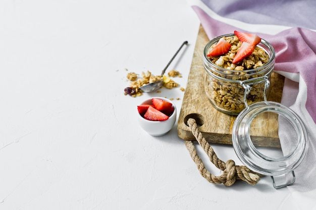 Photo home granola with strawberries in a glass jar.