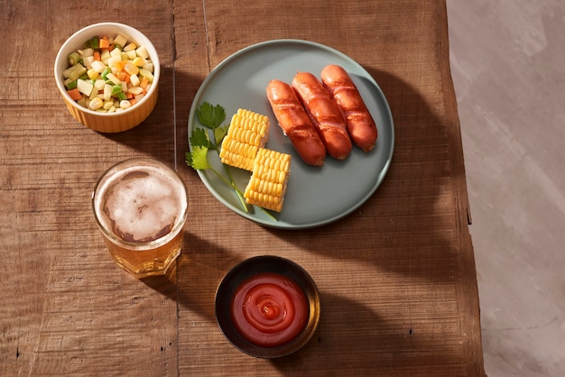 Home grilled sausages on a dark plate, a meat dish on a dark wooden table, hot sausages with spices and salt in a home kitchen, copy space, rustic style, art