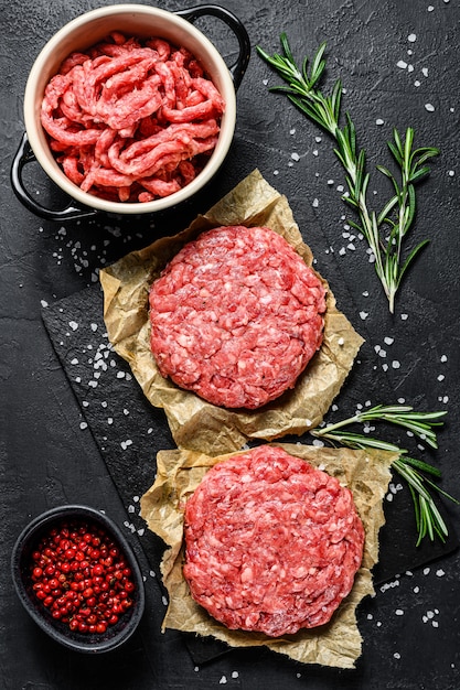 Home handgemaakt rundergehakt steak burgers. boeren biologisch vlees. zwarte achtergrond. bovenaanzicht