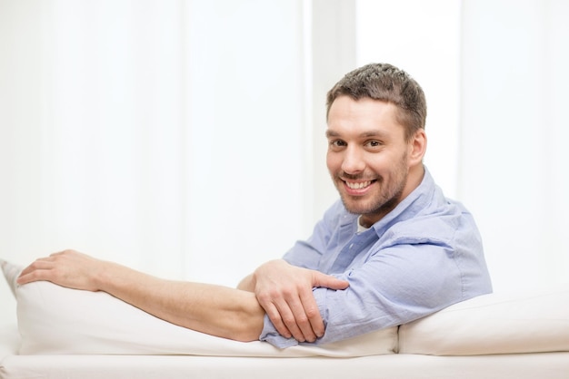 家と幸福の概念-家でソファに座っている笑顔の男