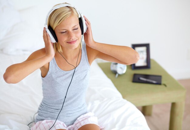 Foto home cuffie e donna con musica camera da letto e streaming suono con radio pace e ascolto zen persona tecnologia e ragazza con cuffie podcast audio e playlist con connessione e canzone