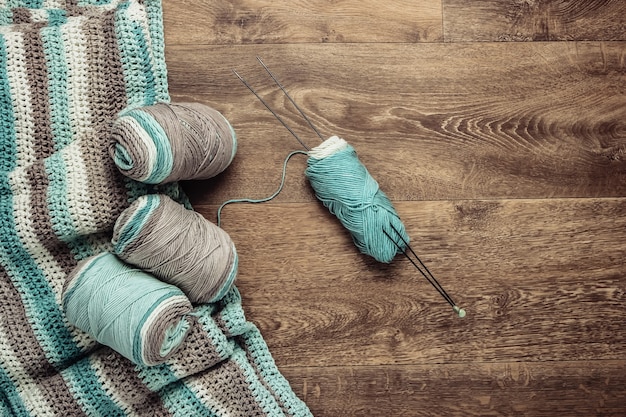 Home hobby. Skeins of woolen threads, yarn, knitted product on the floor. Top view