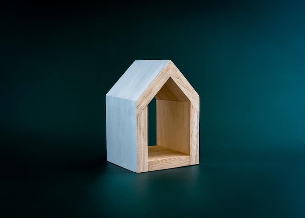 Home huis familie onroerend goed eigendom concepten Wit minimaal miniatuur houten huisje geïsoleerd op donkergroene achtergrond