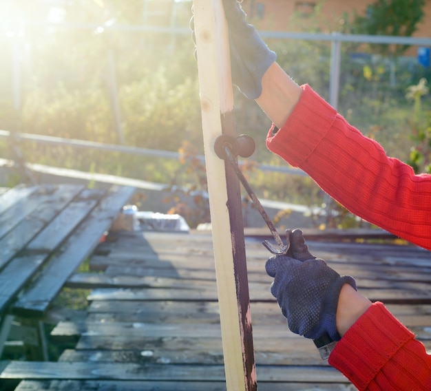 Home improvement handywoman painting wooden plank outdoors