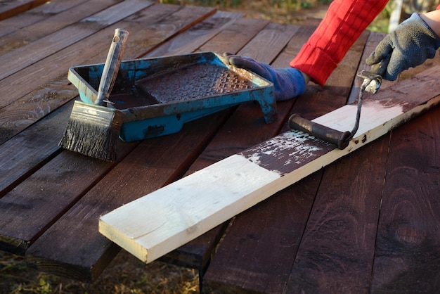 Home improvement handywoman painting wooden plank outdoors