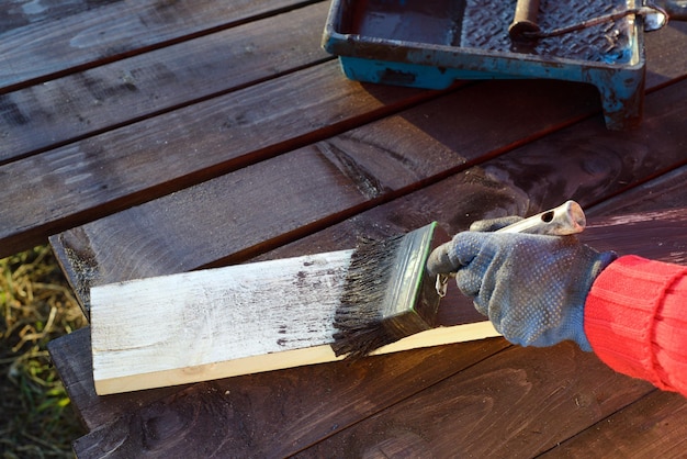 Home improvement handywoman painting wooden plank outdoors