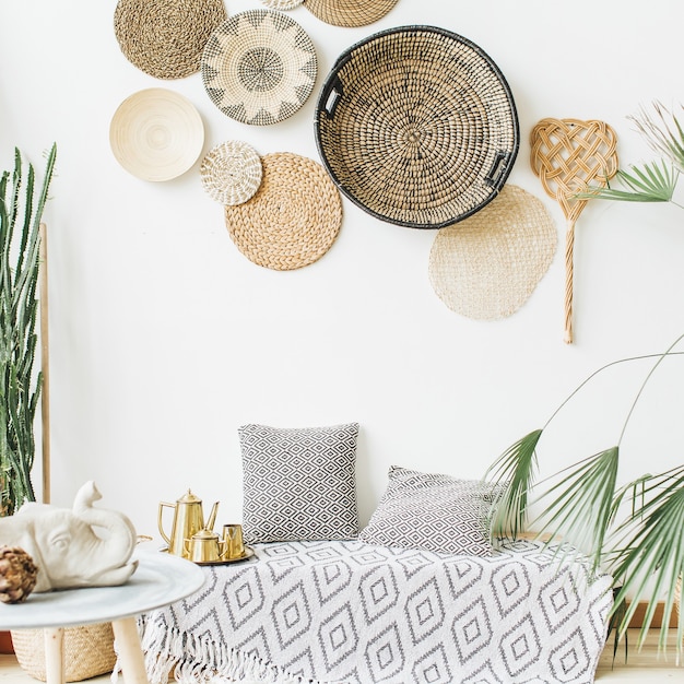 Дизайн домашнего интерьера. Подушки, золотой чайник, декоративные соломенные тарелки, скандинавское одеяло, тропическая пальма, суккуленты и украшения.
