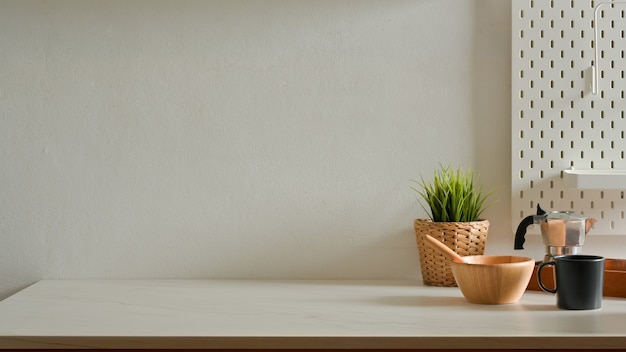 Home interior design with mixed bowl, coffee pot, mug, plant pot and copy space on kitchen table