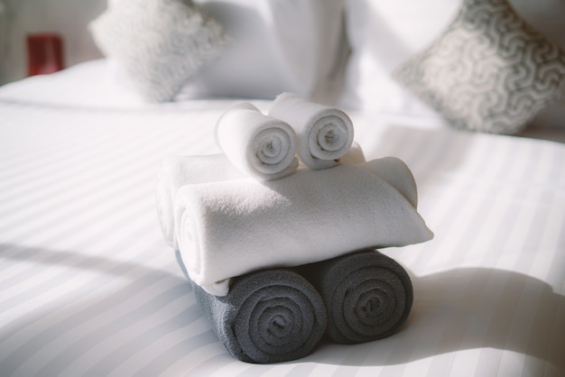 Photo home interior with roll white towels on the bed in the bedroom