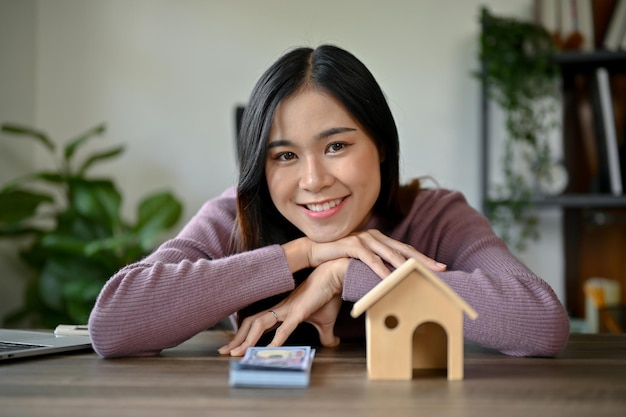 Концепция инвестиций в дом молодая азиатская девушка с моделью дома