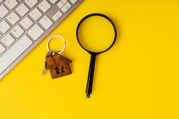 Home key with house magnifying glass and keyboard on a yellow
background real estate online search