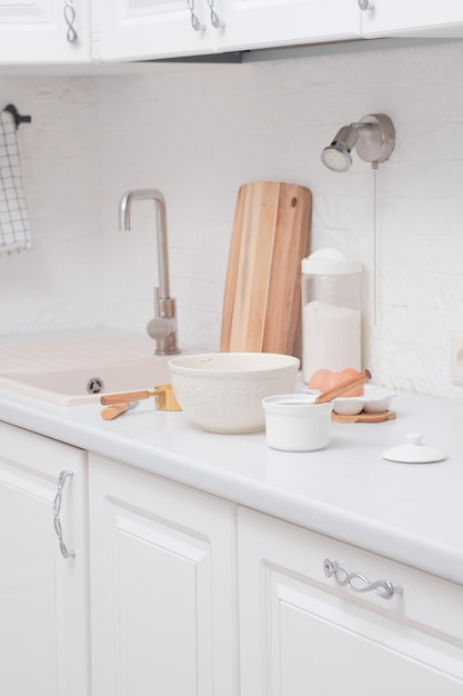 Home kitchen interior bowl with dough and spatula eggs and bowl of sugar napkin knife on kitchen