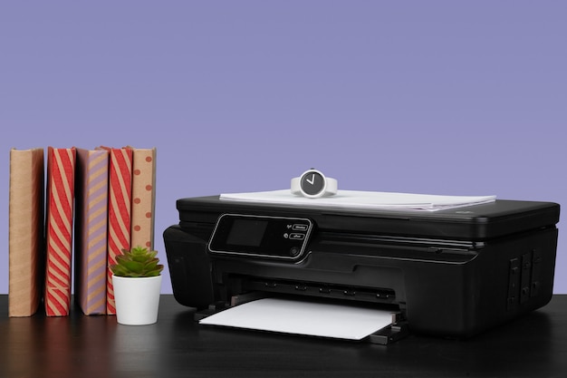 Home laser printer on desk against purple background