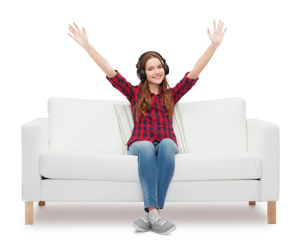 home, leisure and happiness concept - smiling teenage girl sitting on sofa with headphones