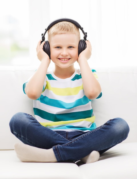 home, leisure, new technology, childhood and music concept - smiling little boy with headphones at home