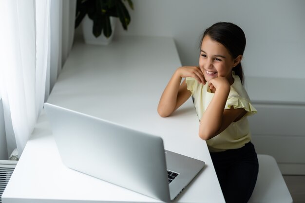 home, leisure, technology and internet concept - little student girl with laptop computer at home, little girl uses video chat