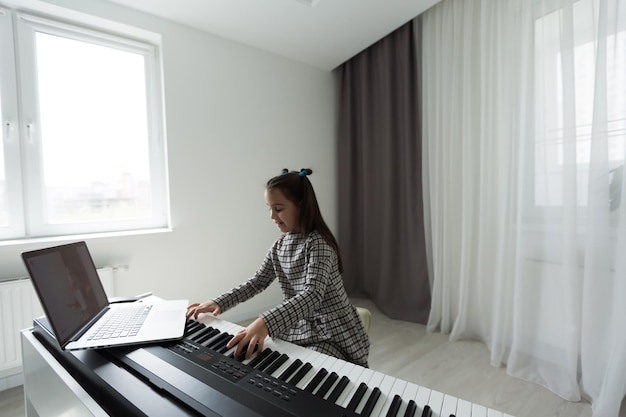 Home lesson on music for the girl on the piano. The idea of activities for the child at home during quarantine. Music concept