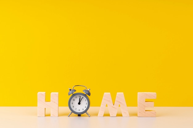 Iscrizione domestica con le lettere e l'orologio di legno su fondo giallo