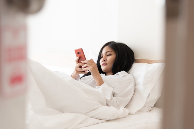  Home lifestyle woman relaxing use mobile on the bed at home 