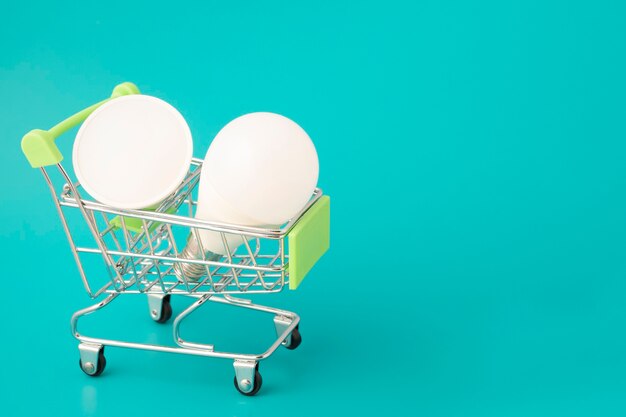 Home lighting, light bulbs in a cart trolley on a green background with copy space