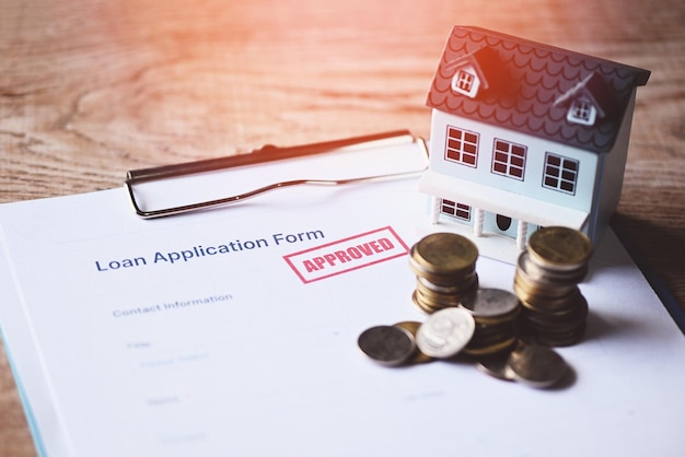 Photo home loan approved on loan application form paper with rubber stamp calculator coin and loan house model on table loan approval business finance economy commercial real estate investments concept