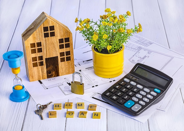 Home loan concept Wooden house calculator hourglass house keys documents design potted flower