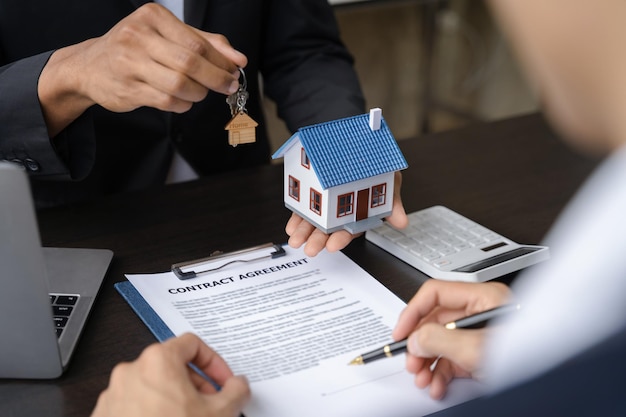 Home loan officer gives the house keys to the client after signing a real estate contract with an approved mortgage application regarding the offer of mortgage loans and home insurance