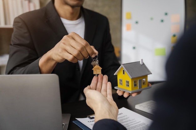 Home loan officer gives the house keys to the client after signing a real estate contract with an approved mortgage application regarding the offer of mortgage loans and home insurance