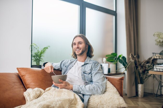 At home. Long-haired man in jeans shirt resting at home