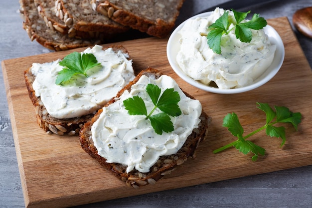 Home made bread on a wooden cutting board with curd cheese and ricotta and herbs Decorated with green herbs