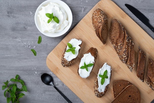 Home made bread on a wooden cutting board with curd cheese and ricotta and herbs Decorated with mint