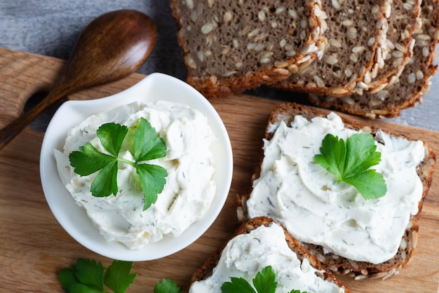 Home made bread on a wooden cutting board with curd cheese and ricotta and herbs