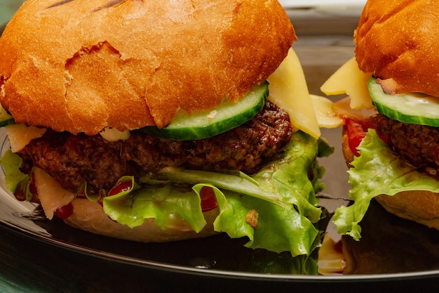 Home made burgers on wooden background. Beef burgers, lettuce, sauce, burger bun on a plate.