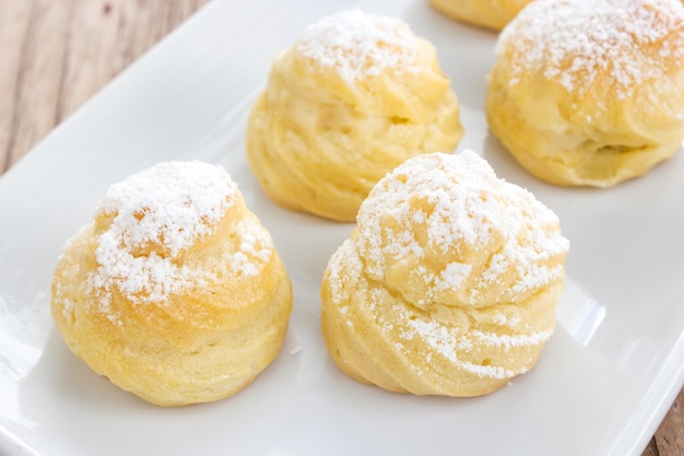 Photo home made choux cream with icing topping on white plate.