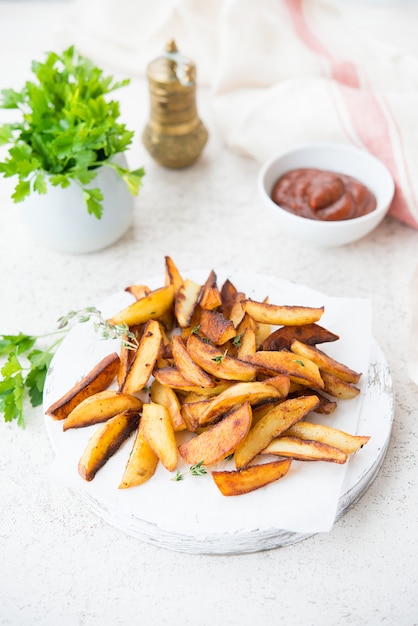 Photo home-made fried potatoes in slices with herbs and ketchup