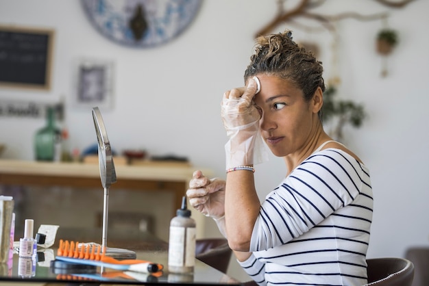 Foto tintura per capelli fatta in casa a casa per la bellezza giovane donna caucasica che si guarda allo specchio - resta a casa concetto per l'emergenza coronavirus contagio pandemico mondiale