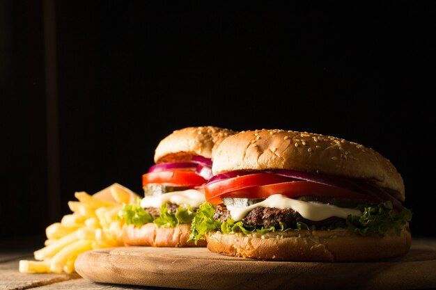 Home made hamburger with beef, onion, tomato, lettuce and cheese. Fresh burger close up on wooden rustic table with potato fries, beer and chips. Cheeseburger.