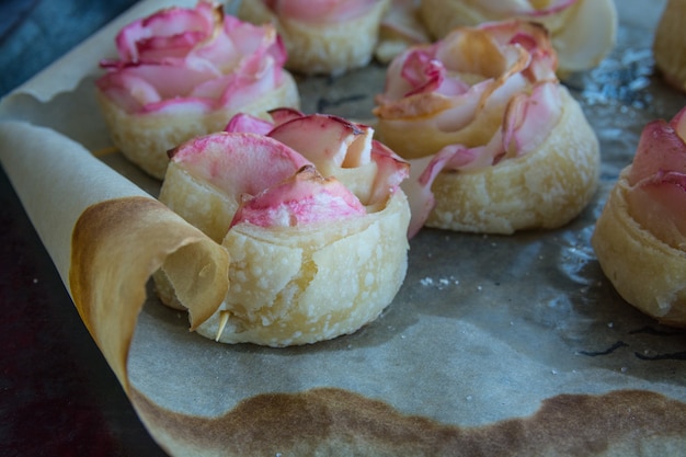 Pasticcini fatti in casa le rose della mela dalla pasta sfoglia su una teglia da forno.