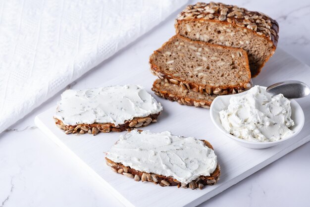 Home made rye bread on a wooden cutting board with curd cheese and ricotta