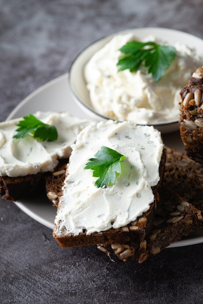 Home made rye bread on a wooden cutting board with curd cheese and ricotta