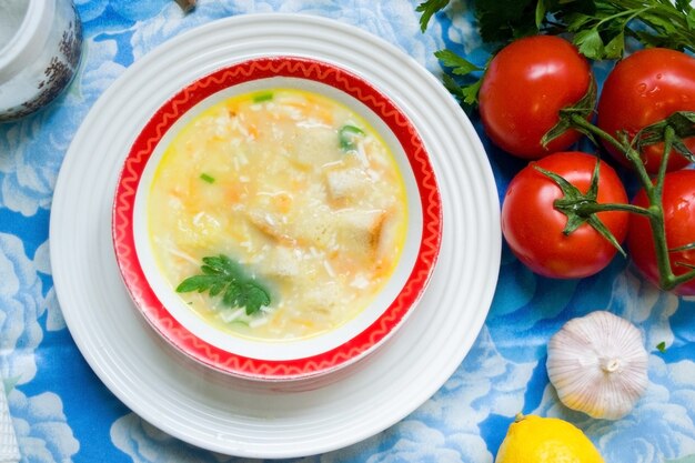 Zuppa fatta in casa in un piatto, su un tavolo con verdure e condimenti