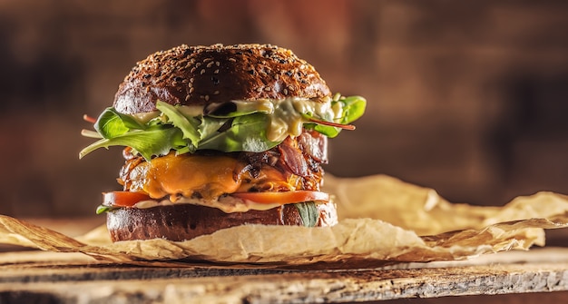 Hamburger saporito fatto in casa con lattuga ane di formaggio cipolla pancetta su scatola di legno.