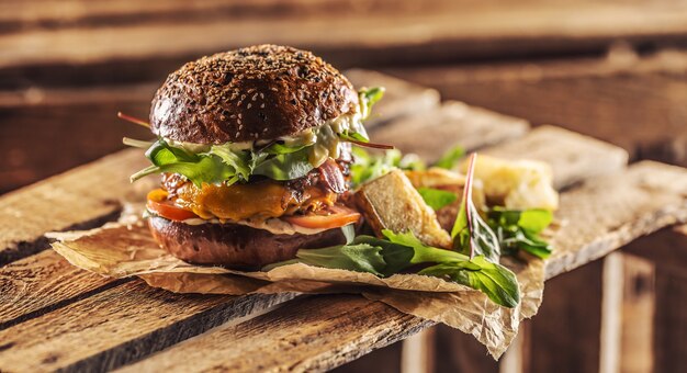 Hamburger saporito fatto in casa con lattuga ane di formaggio cipolla pancetta su scatola di legno.