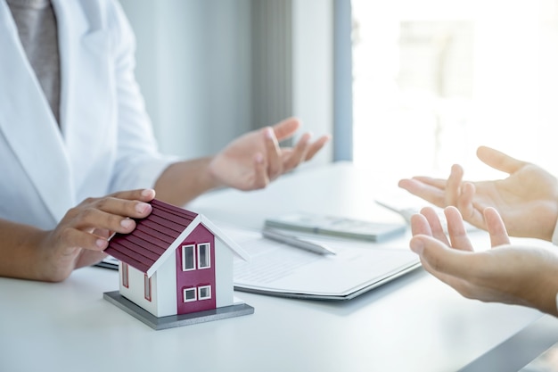 Home model. The real estate agent explains the business contract, rent, purchase, mortgage, a loan, or home insurance to the women buyer.