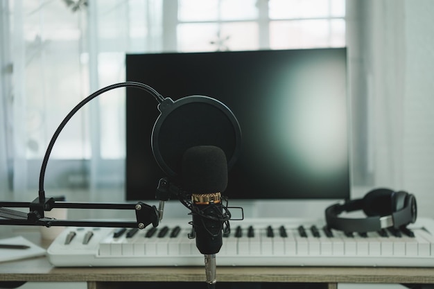 Microfono da studio a condensatore da studio di musica da casa, pianoforte e cuffie bianche per il missaggio di brani di produzione apparecchiature per la registrazione da studio di casa concetto di strumento musicale