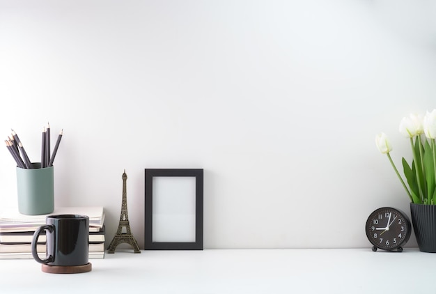 Home office desk with blank picture frame coffee cup books pencil holder and potted plant