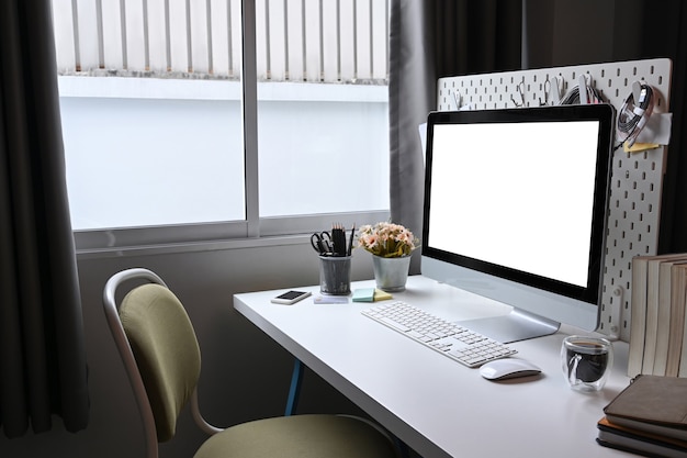 Home office desk with computer, coffee cup and books on white desk.