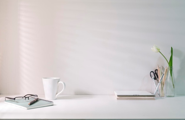 Home office desk with stationery coffee cupglasses and flower pot Copy space for your text