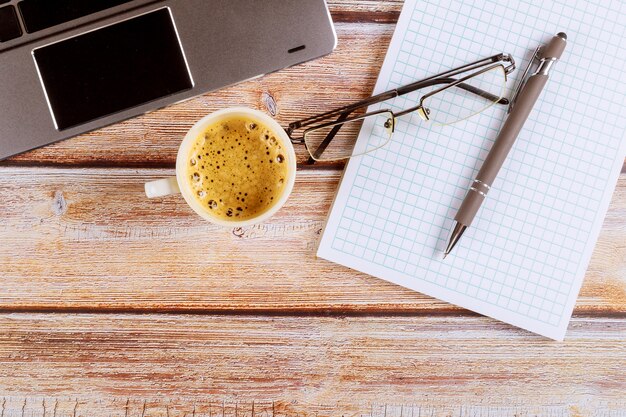 Home office desk workspace with laptop glasses view open notebook, pencil in coffee cup espresso